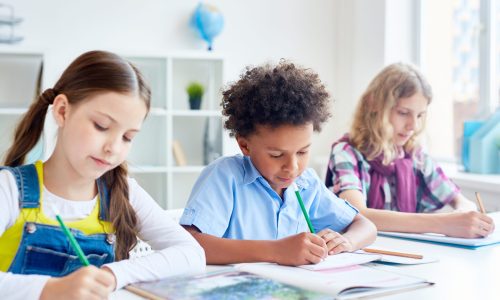 Group of schoolmates with pencils drawing at free topic lesson